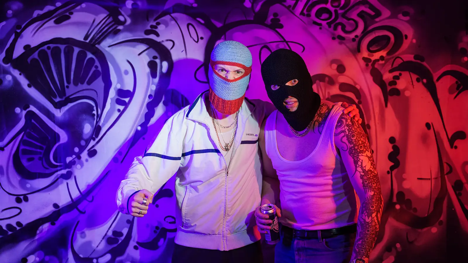 Zwei maskierte Personen vor Graffiti‑Wand, Neonlicht in Blau und Pink, halten Sprühdose.