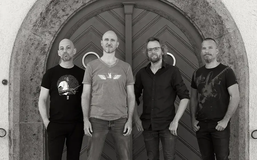 Pressefoto des Vlado Grizelj Quartetts mit vier Musikern vor einem großen Rundbogenportal, in Schwarzweißaufnahme mit dunkler Freizeitkleidung vor einer historischen Tür.