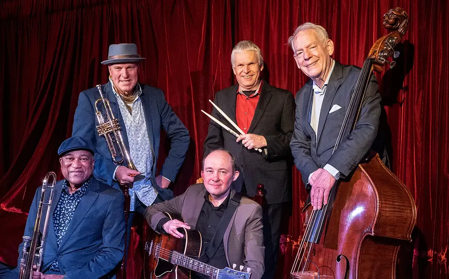 Foto der Band The Hot Stuff Jazzband, auf der die Mitglieder mit ihren Instrumenten zu sehen sind.