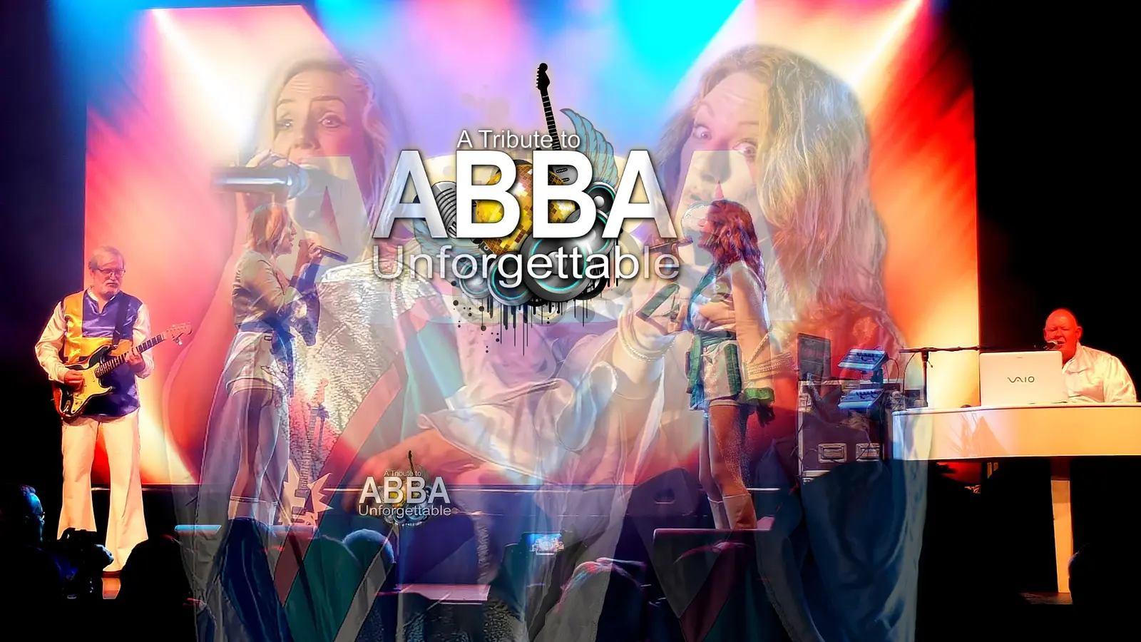 Bühnenbild mit Musikern und Sängerinnen, bunt beleuchtet. Links Gitarre, rechts Keyboard, in der Mitte große Projektion mit Text: A Tribute to ABBA – Unforgettable