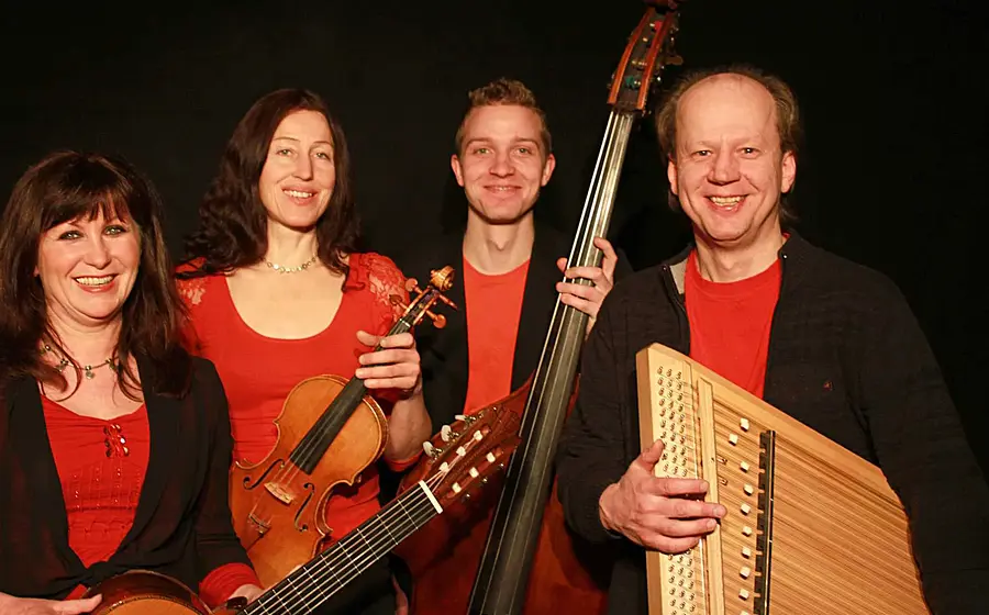 Bandfoto eines Ensembles mit Rudi Zapf und drei Musikerinnen und Musikern vor schwarzem Hintergrund, in rot schwarzen Outfits, mit Instrumenten wie Violine, Gitarre, Kontrabass und Zither in den Händen.