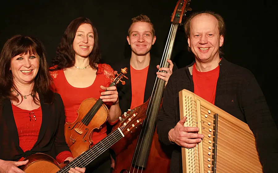 Welt-Weihnachtskonzert Rudi Zapf & Freunde: Vier Musiker mit Violine, Kontrabass, Gitarre und Hackbrett stehen nebeneinander vor schwarzem Hintergrund.
