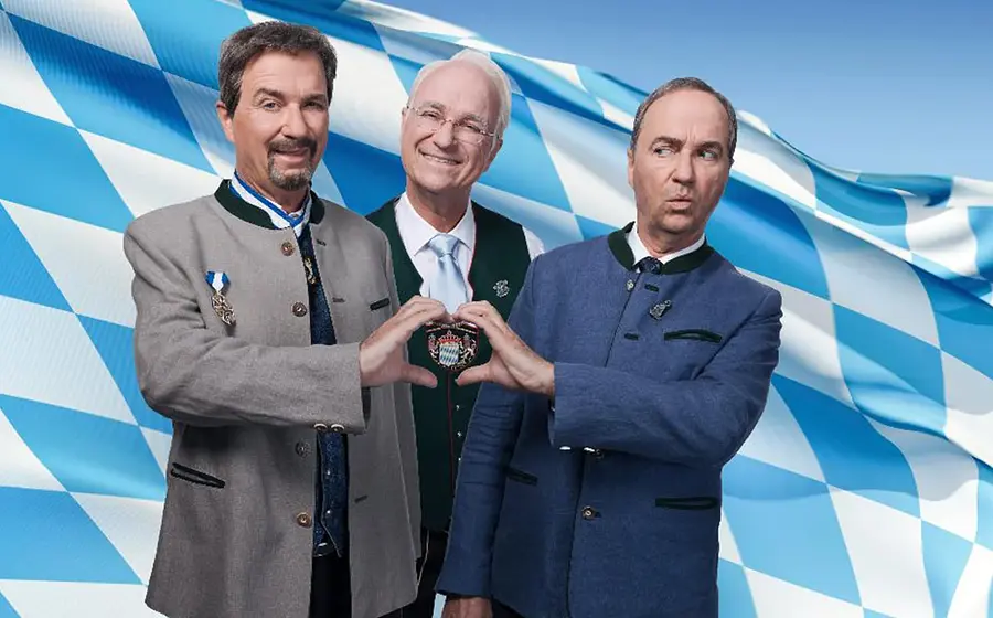 Foto für die Veranstaltung Wolfgang Krebs mit drei Männern und der bayerischen Flagge im Hintergrund.