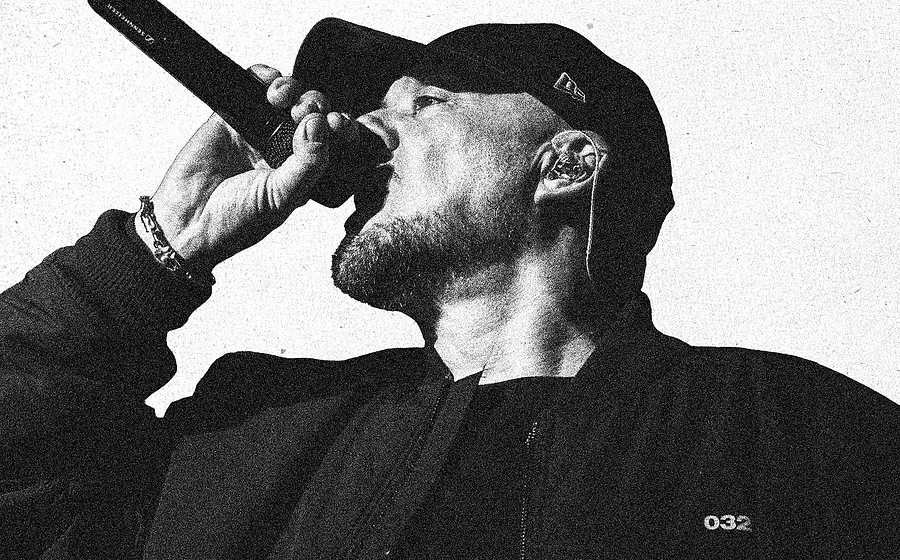 KOOL SAVAS mit Cap singt ins Mikrofon, Schwarz-Weiß‑Foto.