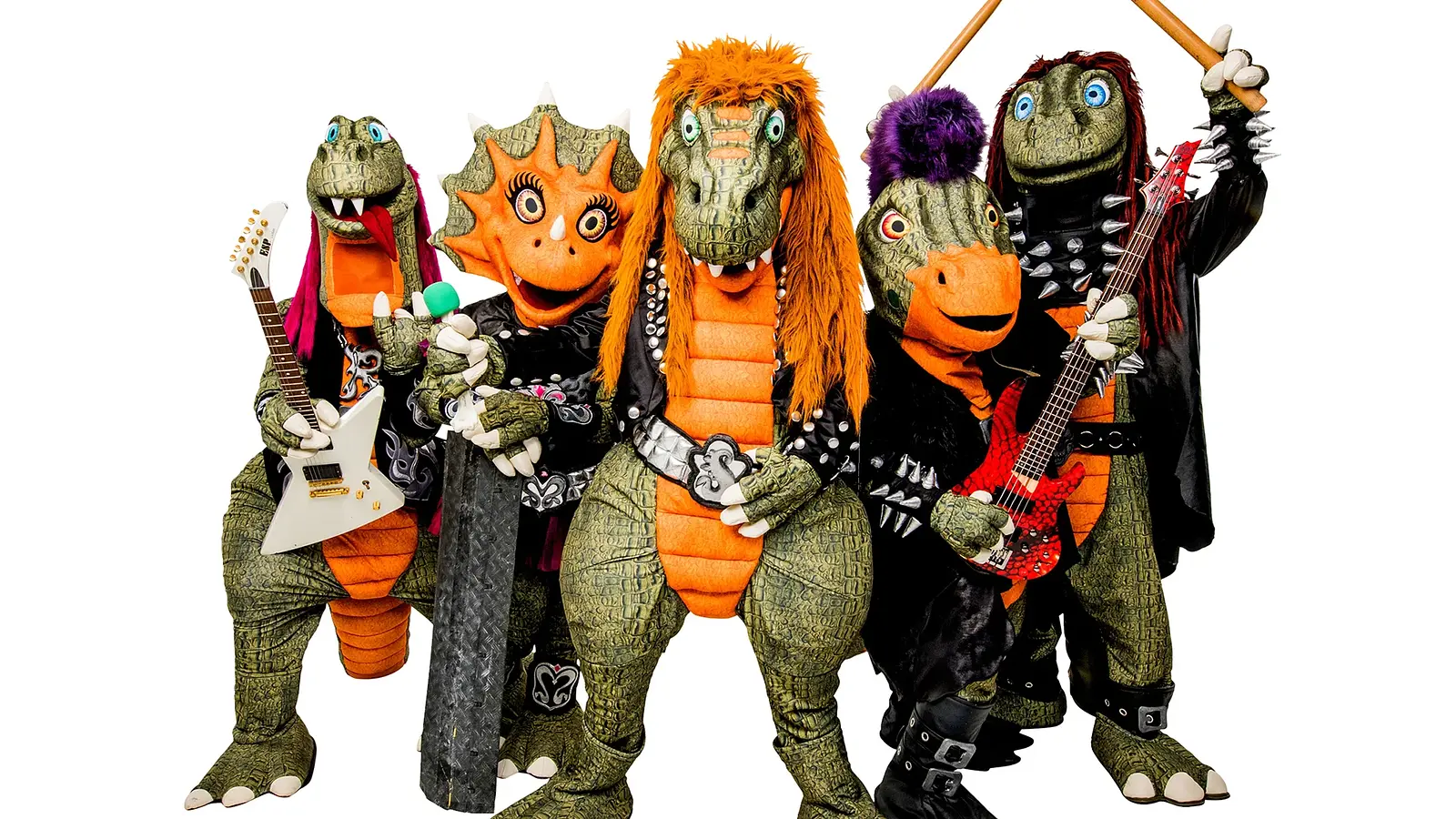 Pressefoto von Heavysaurus mit fünf Dinosaurierfiguren in Rockkostümen vor hellem Hintergrund, darunter E-Gitarren und Drumsticks, mit bunten Haaren, Nieten und schwarzen Bühnenoutfits