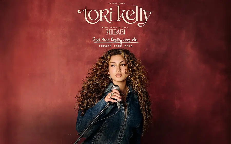 Plakat von Tori Kelly mit Mikrofon in der Hand vor rotbraunem Hintergrund, darüber die Schriftzüge Tori Kelly, God Must Really Love Me Europe Tour 2026 sowie Special Guest Hillari.