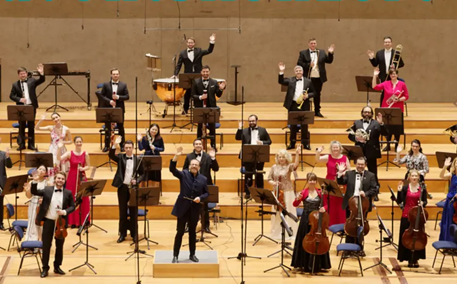 Ein Orchester mit Instrumenten  auf einer breiten Bühne mit Treppen während einer Vorführung