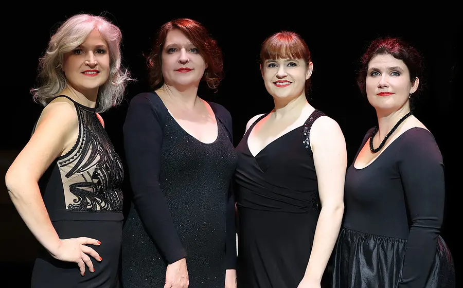 Foto für die Veranstaltung von Vokal Total – Aquabella, mit vier Frauen in Schwarz gekleidet vor schwarzem Hintergrund