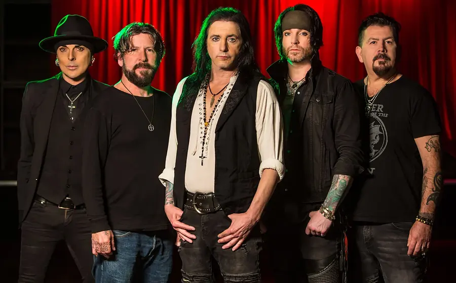 Foto für die Veranstaltung L.A. GUNS mit der komplett in Schwarz gekleideten Band vor roten Vorhängen auf einer Bühne.