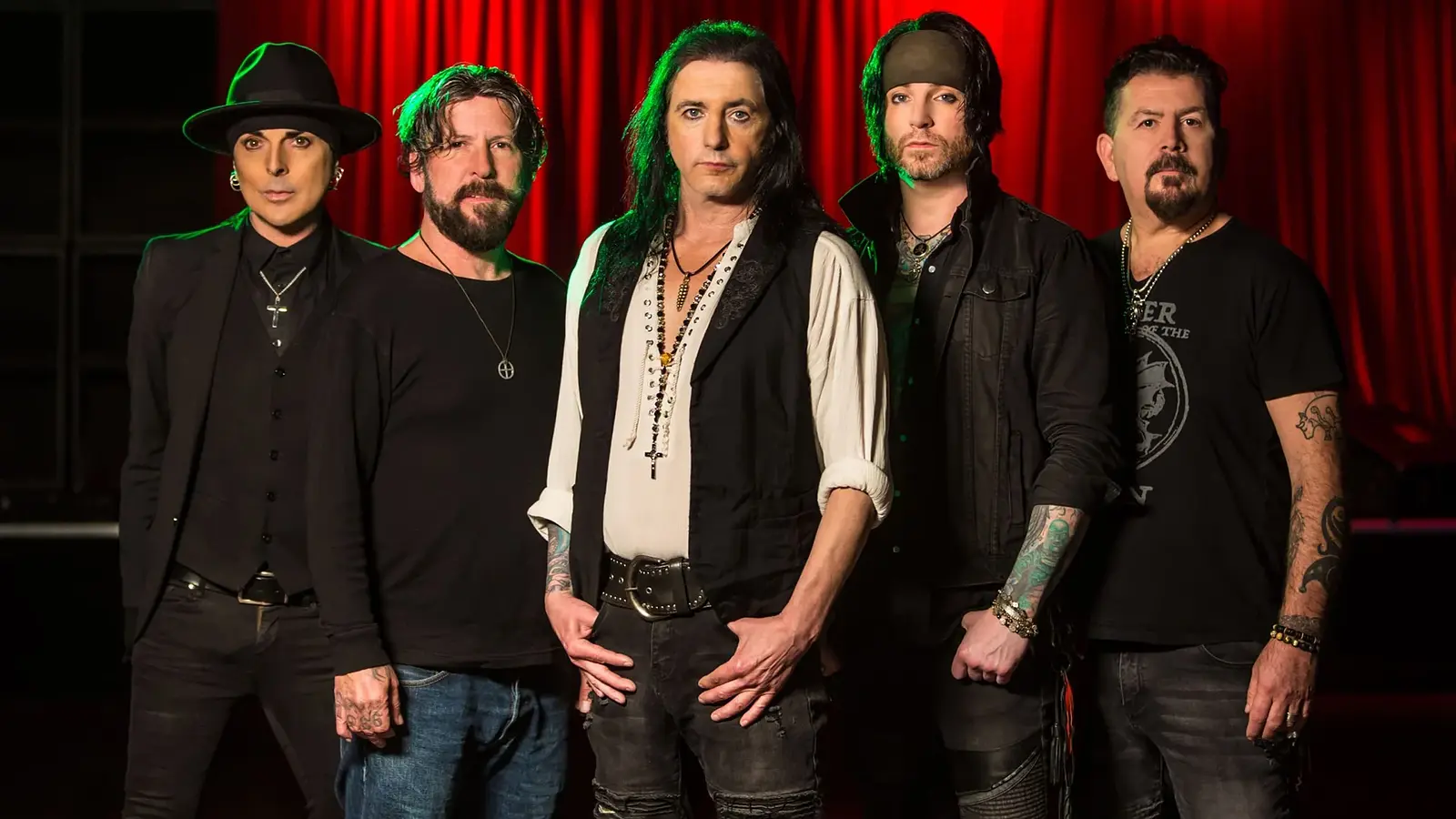 Foto für die Veranstaltung L.A. GUNS mit der komplett in Schwarz gekleideten Band vor roten Vorhängen auf einer Bühne.