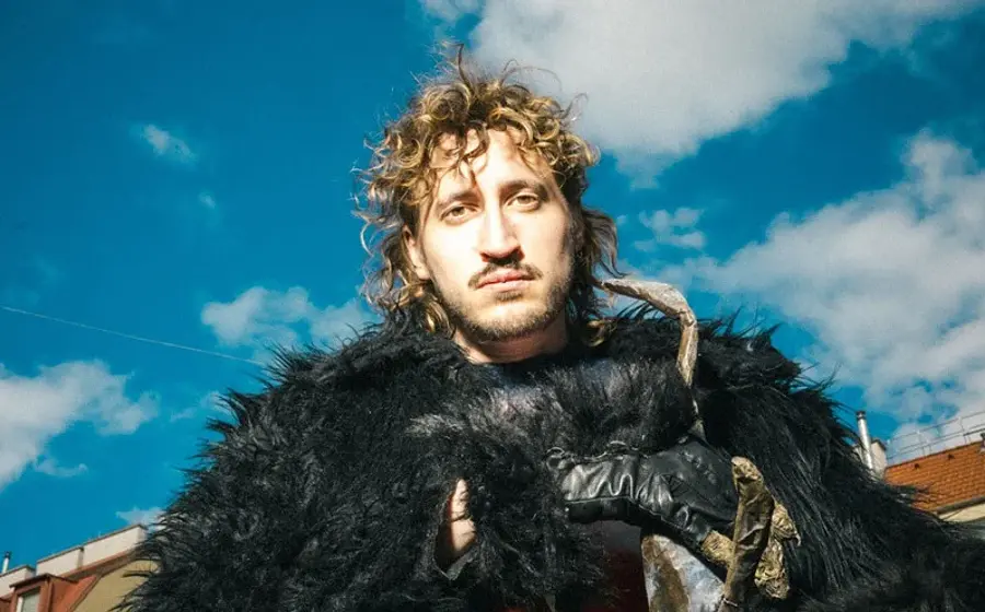 Foto eines Jungen mit einer schwarzen Pelzjacke und einem blauen Himmel im Hintergrund