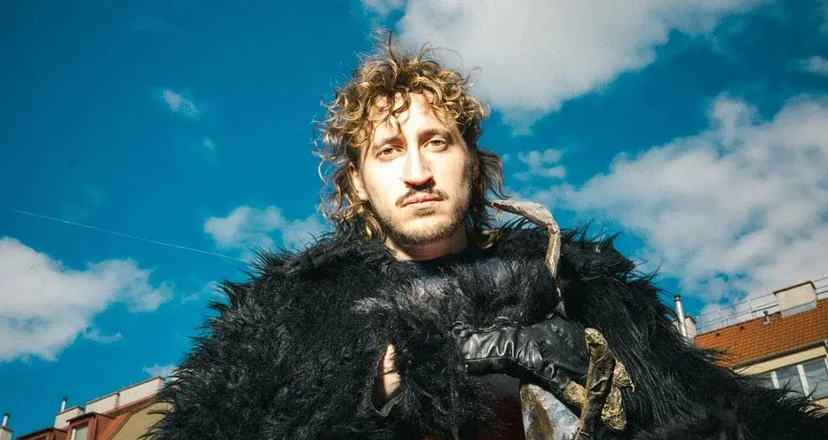 Foto eines Jungen mit einer schwarzen Pelzjacke und einem blauen Himmel im Hintergrund