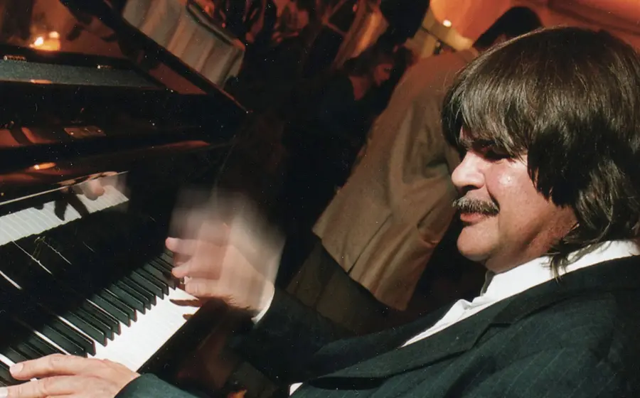 Axel Zwingenberger in schwarzem Anzug spielt am Klavier, eine Hand in Bewegung