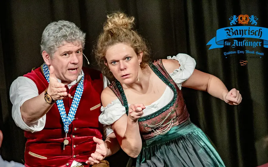 Foto für die Veranstaltung ‚Bayrisch für Anfänger – Comedy Dinner‘ mit einem Mann und einer Frau in traditioneller bayerischer Tracht