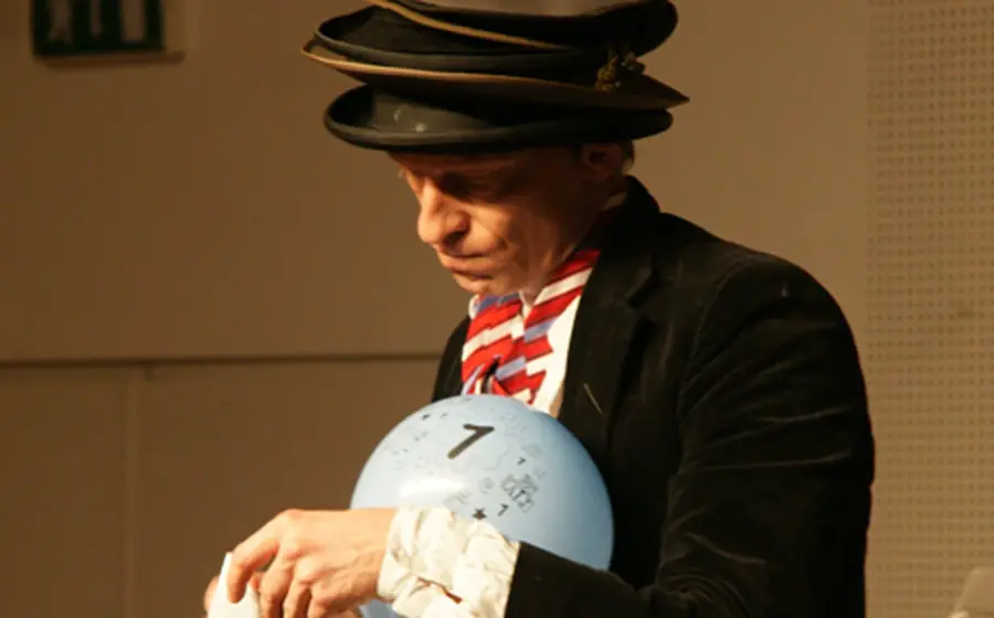 Foto von der Veranstaltung „Die Ver(w)irrung des Nepermuk Semmelmeier“ mit einem Ball und mehreren Hüten, die übereinander gestapelt sind.