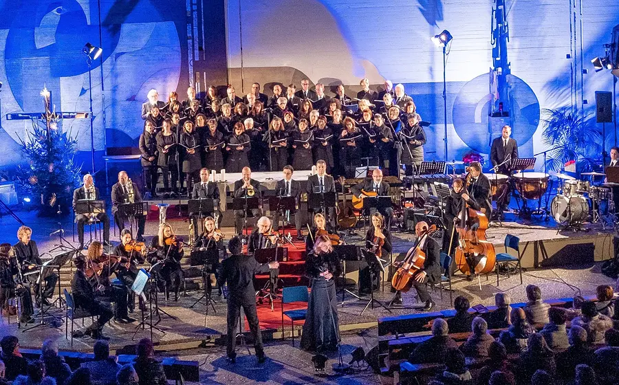 Chor und Orchester bei einem festlichen Weihnachtskonzert vor Publikum.
