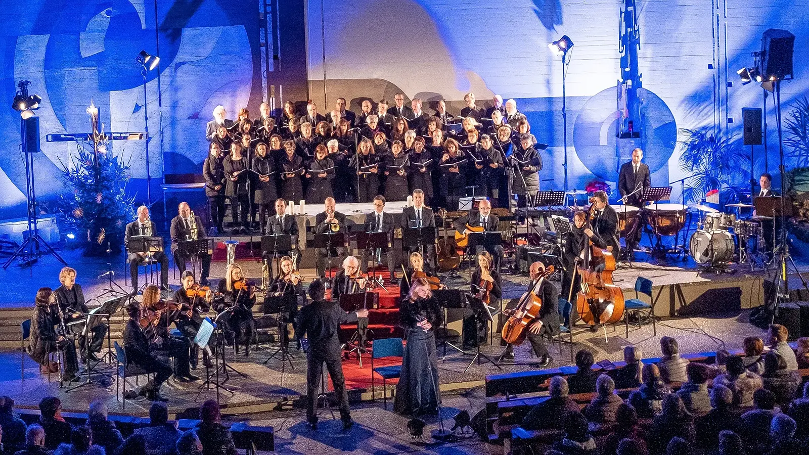 Chor und Orchester bei einem festlichen Weihnachtskonzert vor Publikum.