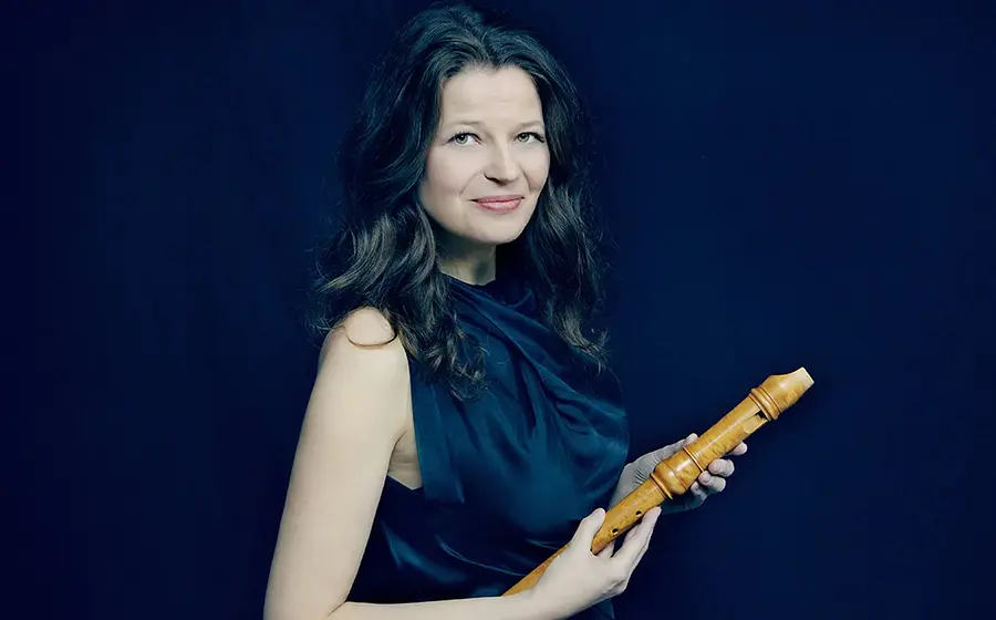 Dorothee Oberlinger mit Flöte in der Hand in einem dunkelblauen Kleid vor dunkelblauem Hintergrund