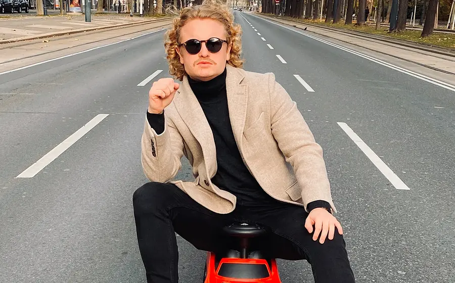 Der Künstler sitzt auf einem Spielzeugauto auf einer Straße