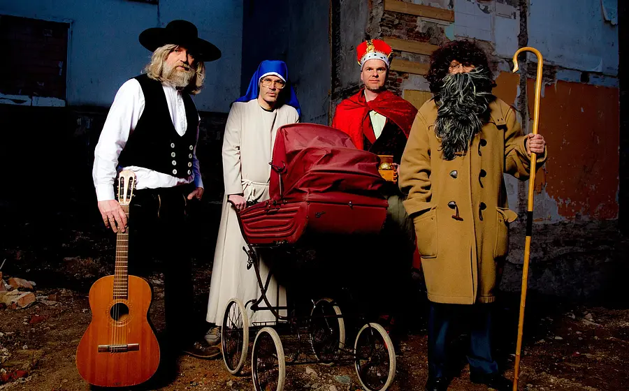 Vier Darsteller, verkleidet als Bettler, Nonne, Priester und Musiker vor Hinterhof-Kulisse
