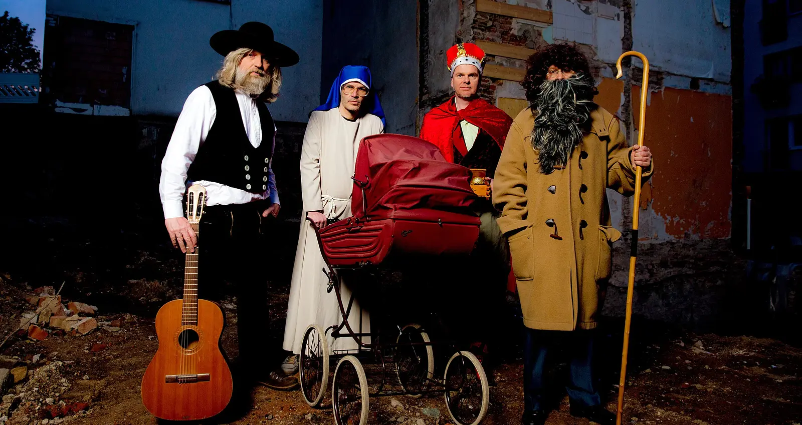 Vier Darsteller, verkleidet als Bettler, Nonne, Priester und Musiker vor Hinterhof-Kulisse