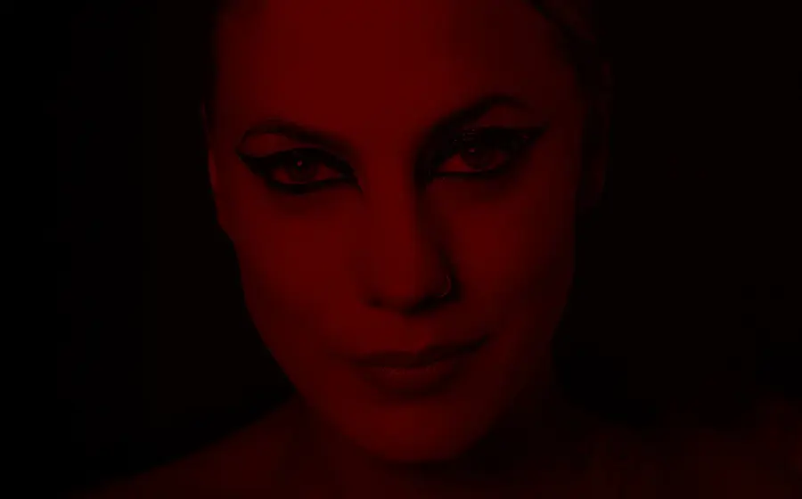 Ein Portrait der Künstlerin Lafee mit stark geschminkten Augen, ihr Gesicht in dunklem rot mit dunklem Hintergrund