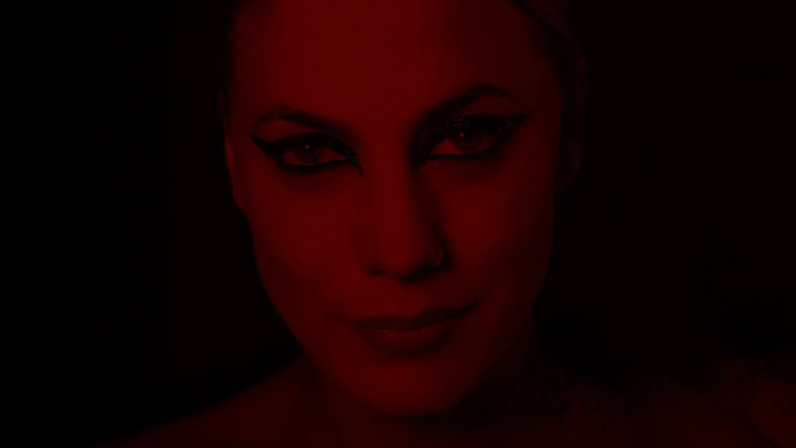 Ein Portrait der Künstlerin Lafee mit stark geschminkten Augen, ihr Gesicht in dunklem rot mit dunklem Hintergrund