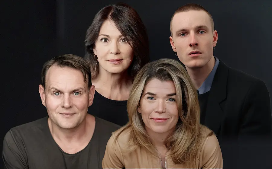 Gruppenporträt von vier Personen vor dunklem Hintergrund, die direkt in die Kamera blicken.