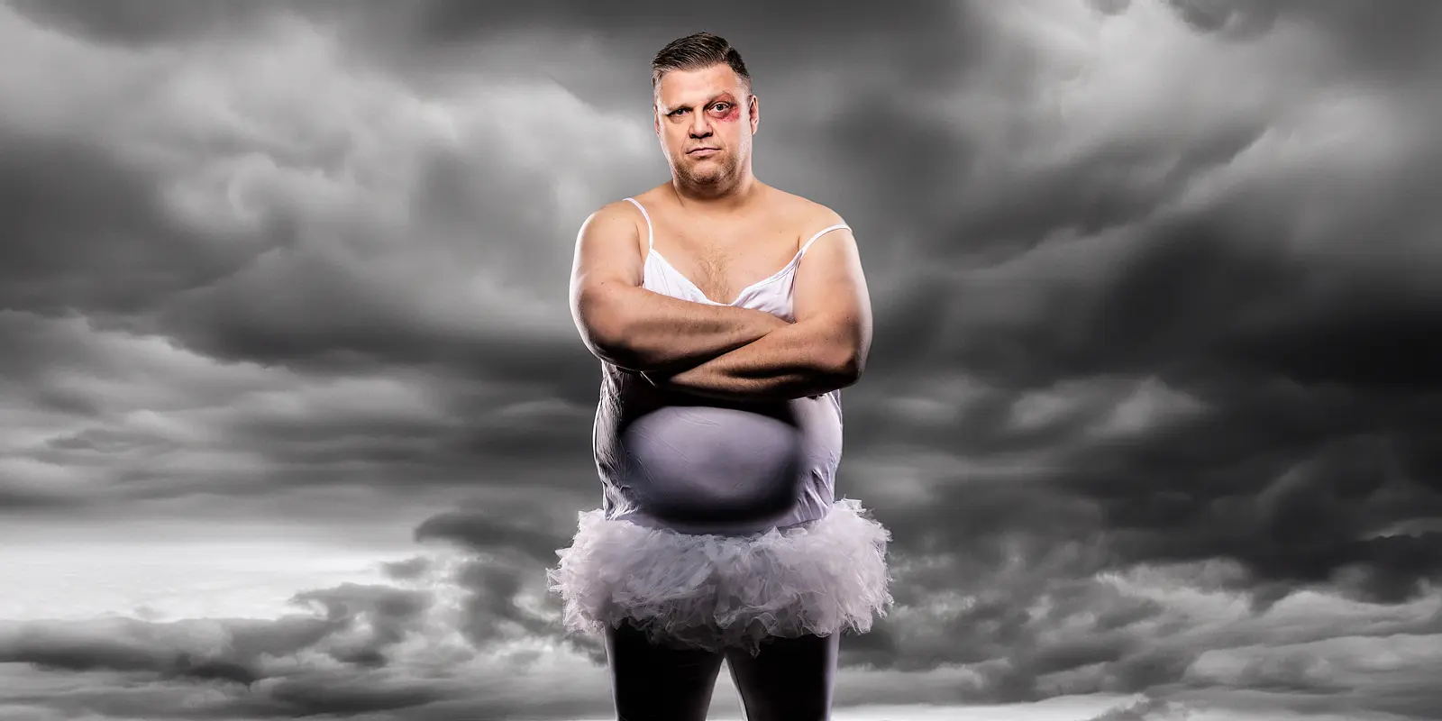 Foto von Ralf Winkelbeiner im fliederfarbenen Kleid mit einem blauen Auge. Im Hintergrund graue Wolken