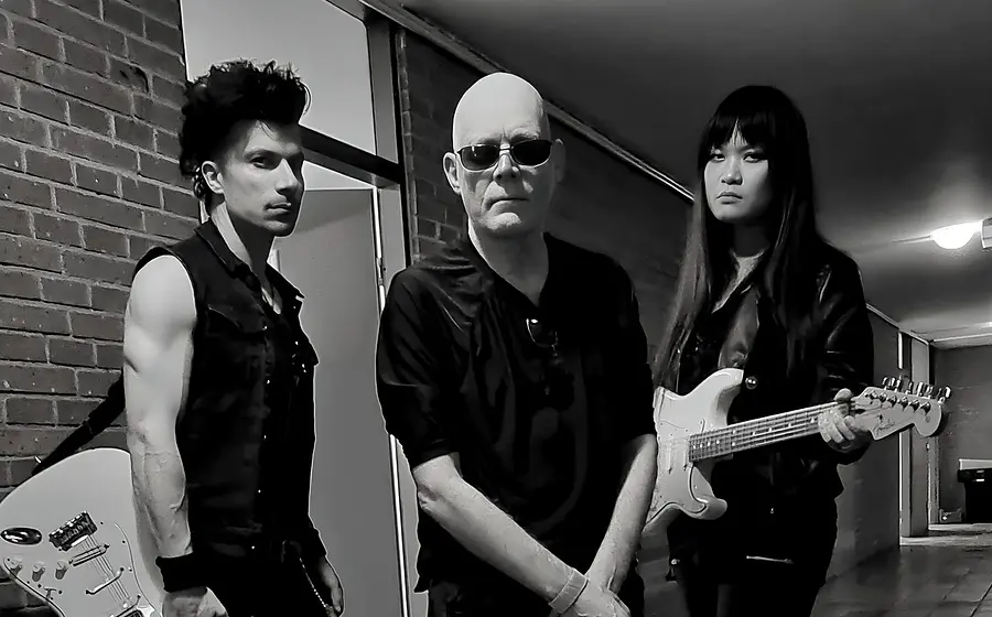 Schwarz‑Weiß‑Foto für das Event von THE SISTERS OF MERCY mit den drei Künstlern mit E‑Gitarren