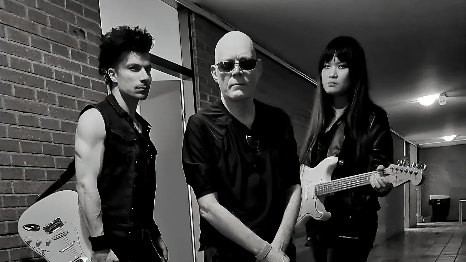 Schwarz‑Weiß‑Foto für das Event von THE SISTERS OF MERCY mit den drei Künstlern mit E‑Gitarren