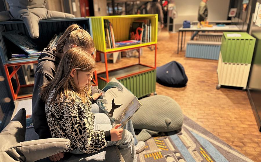 Zwei Kinder schauen sich auf der Mitmachinsel in der Schifffahrtsausstellung im Deutschen Technikmuseum ein Buch an.