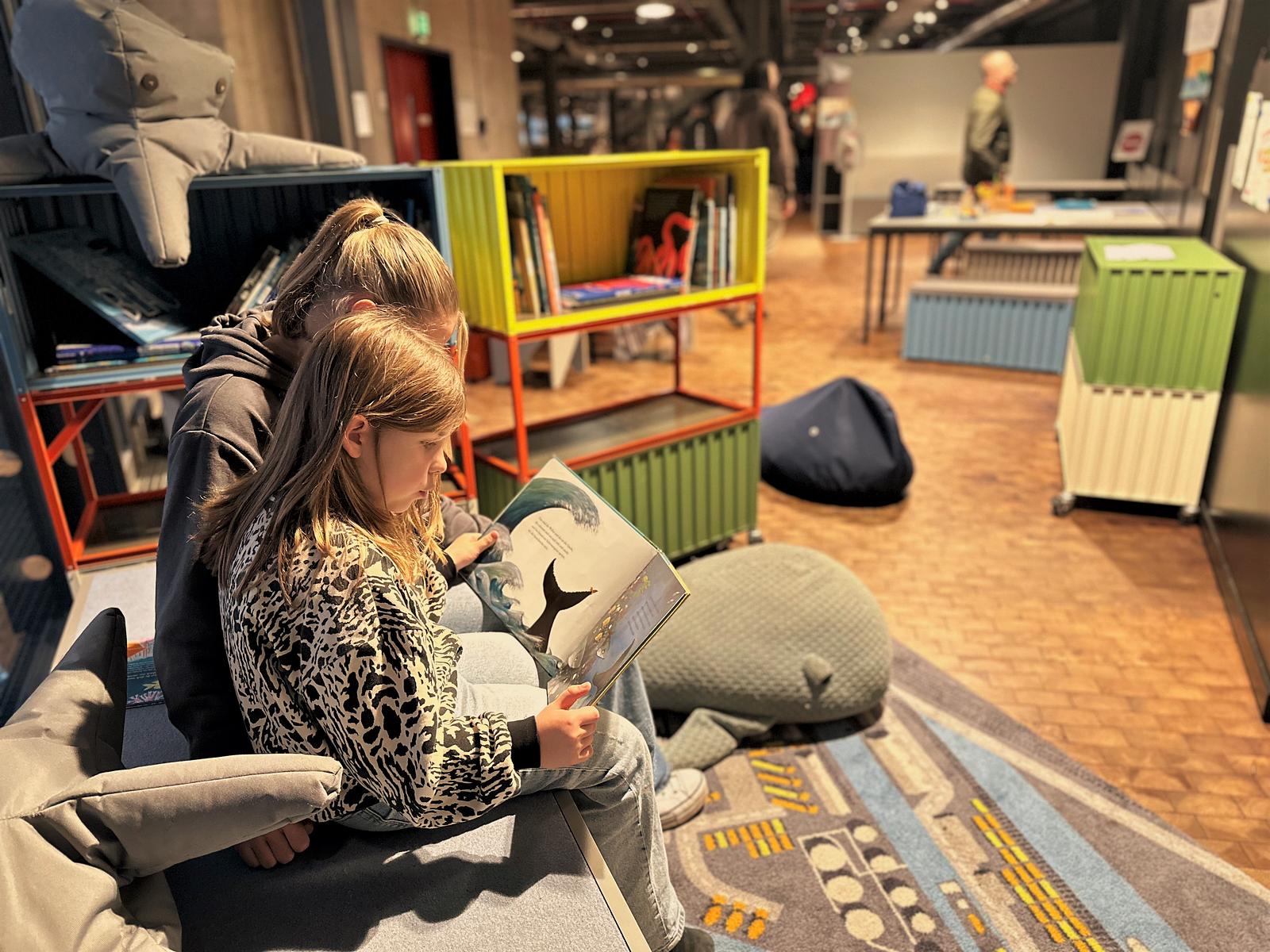 Zwei Kinder schauen sich auf der Mitmachinsel in der Schifffahrtsausstellung im Deutschen Technikmuseum ein Buch an.