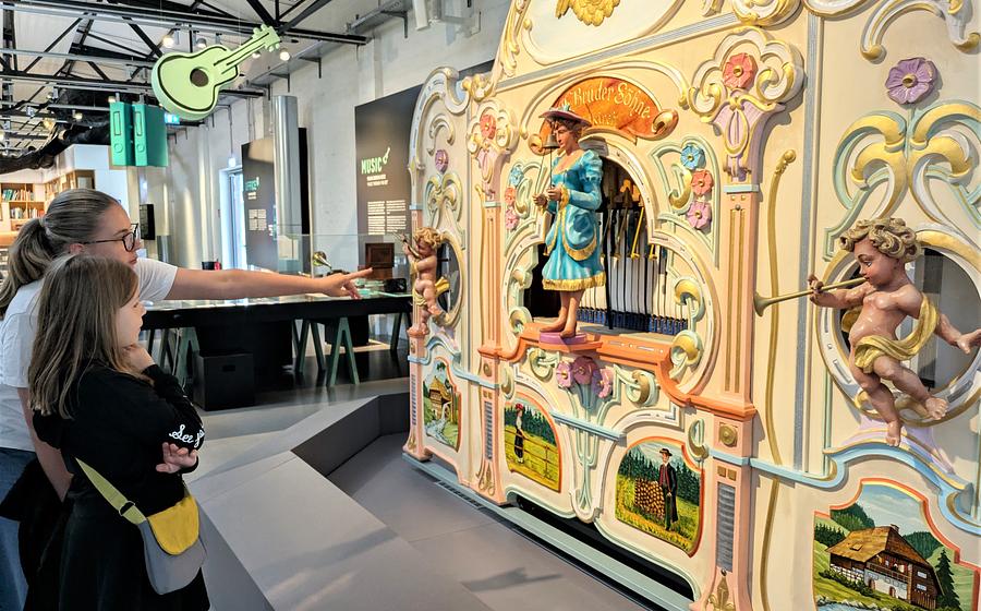 Zwei Mädchen stehen in der Dauerausstellung "Das Netz" vor einer bunten, historischen Orgel.